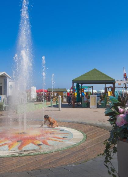 Brunnen auf einem Spielplatz in der Nähe des Strandes, mit bunten Kabinen.