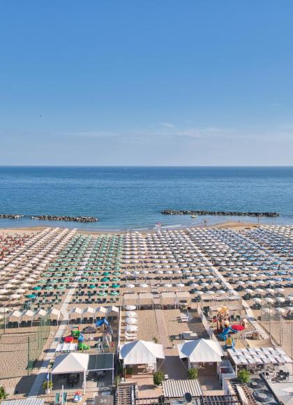 Überfüllter Strand mit bunten Sonnenschirmen und ruhigem Meer.