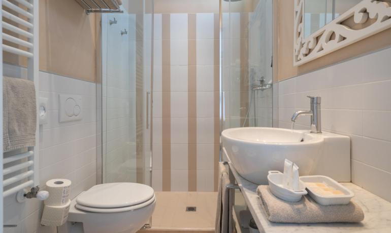 Bagno moderno con doccia, lavabo, WC e specchio decorativo.
