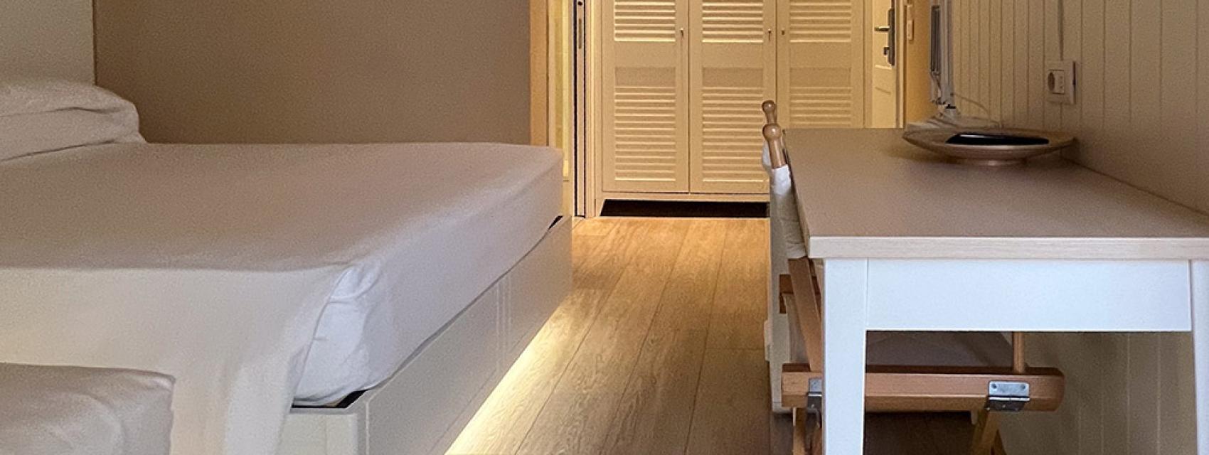 Modernes Hotelzimmer mit Bett, Schreibtisch und Kleiderschrank.