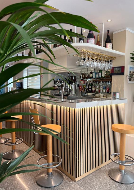 Moderne Bar mit Holzstühlen und hängenden Gläsern.